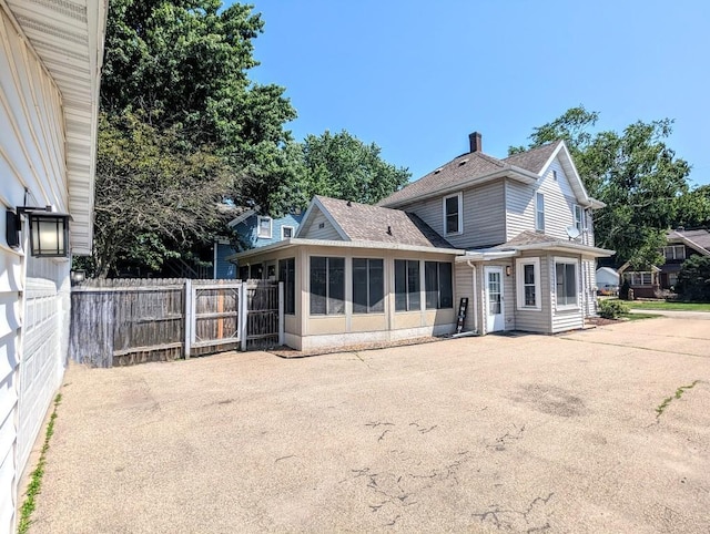 232 4th St, Neenah, WI 54956 - rear view of property featuring a sunroom, a shingled roof, and a chimney