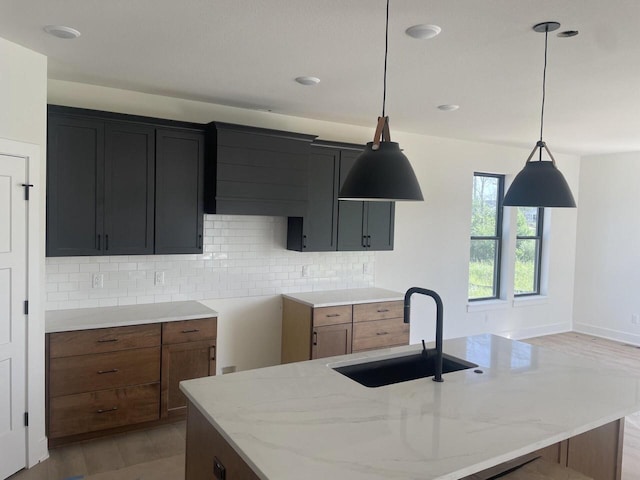N75W17841 Woody Ln, Menomonee Falls, WI 53051 - kitchen with light stone countertops, decorative backsplash, hanging light fixtures, and an island with sink