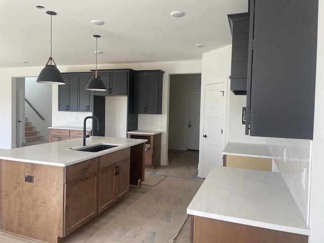 N75W17841 Woody Ln, Menomonee Falls, WI 53051 - kitchen with tasteful backsplash, a kitchen island with sink, decorative light fixtures, and light stone counters