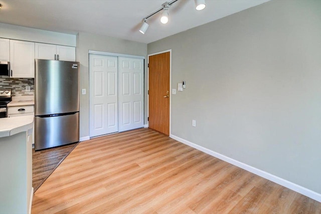 201 Kearney Way Unit 201, Waunakee, WI 53597 - kitchen with appliances with stainless steel finishes, light countertops, light wood finished floors, white cabinets, and tasteful backsplash