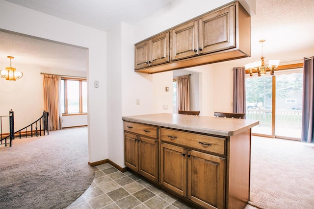 403 Bluebird Ln, Loyal, WI 54446 - kitchen featuring a chandelier, dark colored carpet, a peninsula, decorative light fixtures, and brown cabinetry
