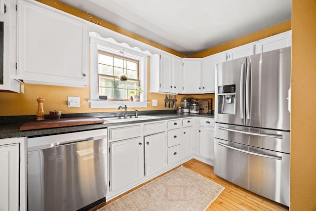 622 Grant St, Fort Atkinson, WI 53538 - kitchen featuring appliances with stainless steel finishes, dark countertops, light wood-style floors, and white cabinetry