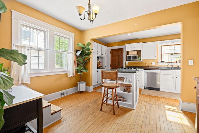622 Grant St, Fort Atkinson, WI 53538 - kitchen with appliances with stainless steel finishes, light wood-style flooring, white cabinetry, and a chandelier