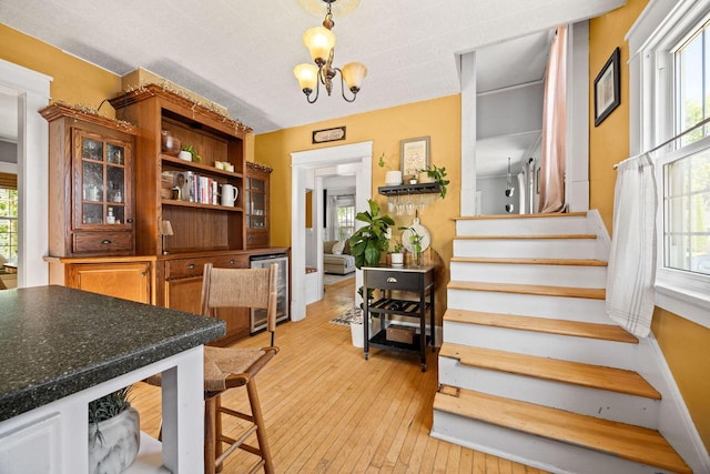 622 Grant St, Fort Atkinson, WI 53538 - dining area featuring beverage cooler, stairway, light wood-type flooring, and healthy amount of natural light