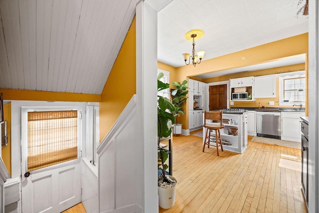 622 Grant St, Fort Atkinson, WI 53538 - kitchen with appliances with stainless steel finishes, white cabinetry, a chandelier, and light wood-style flooring