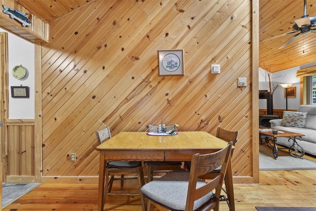 17705 Nicolet Rd, Townsend, WI 54175 - dining space featuring wood walls, light wood-style floors, vaulted ceiling, a ceiling fan, and a wood stove