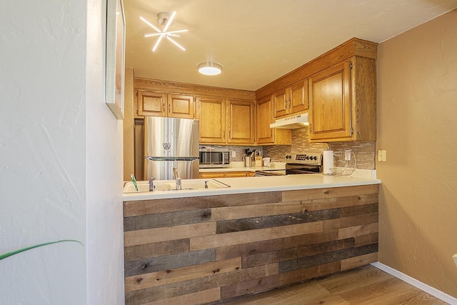 630 Brule Rd Unit 11, De Pere, WI 54115 - kitchen with stainless steel appliances, decorative backsplash, wood finished floors, under cabinet range hood, and light countertops