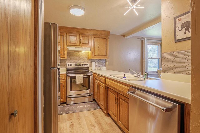 630 Brule Rd Unit 11, De Pere, WI 54115 - kitchen with appliances with stainless steel finishes, light wood-style floors, light countertops, backsplash, and under cabinet range hood