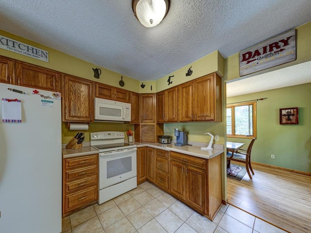 10811 S Patterson Rd, Solon Springs, WI 54873 - kitchen with white appliances, light countertops, brown cabinets, light tile patterned floors, and a textured ceiling