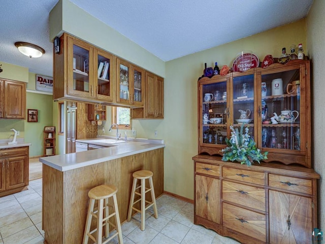10811 S Patterson Rd, Solon Springs, WI 54873 - kitchen with glass insert cabinets, a kitchen breakfast bar, a textured ceiling, light tile patterned flooring, and light countertops