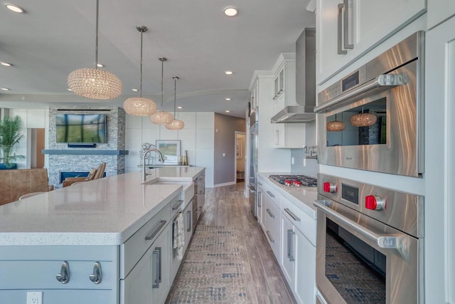 215 E Pleasant St Unit 304, Oconomowoc, WI 53066 - kitchen featuring wall chimney range hood, light wood-style floors, stainless steel appliances, recessed lighting, and white cabinets
