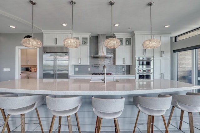 215 E Pleasant St Unit 304, Oconomowoc, WI 53066 - kitchen with wall chimney range hood, stainless steel appliances, a spacious island, decorative backsplash, and white cabinets