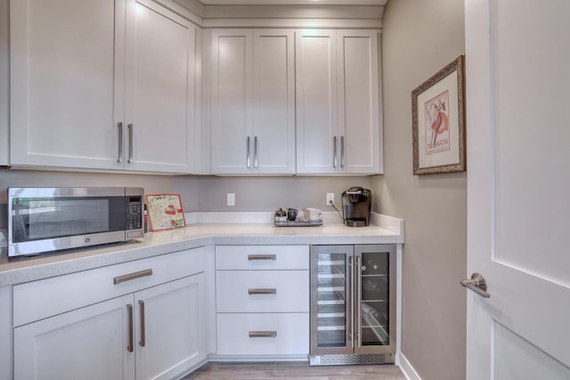215 E Pleasant St Unit 304, Oconomowoc, WI 53066 - bar area with wine cooler, stainless steel microwave, and light wood-type flooring
