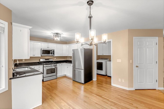 2855 River Birch Dr Unit D, Brookfield, WI 53045 - kitchen featuring stainless steel appliances, washer and dryer, dark countertops, light wood-style flooring, and white cabinets