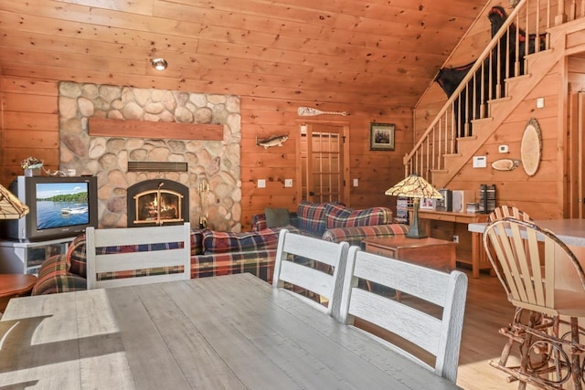 1780 Amik Lake Ln, Lac Du Flambeau, WI 54538 - dining space featuring wood walls, wood finished floors, stairs, lofted ceiling, and a fireplace