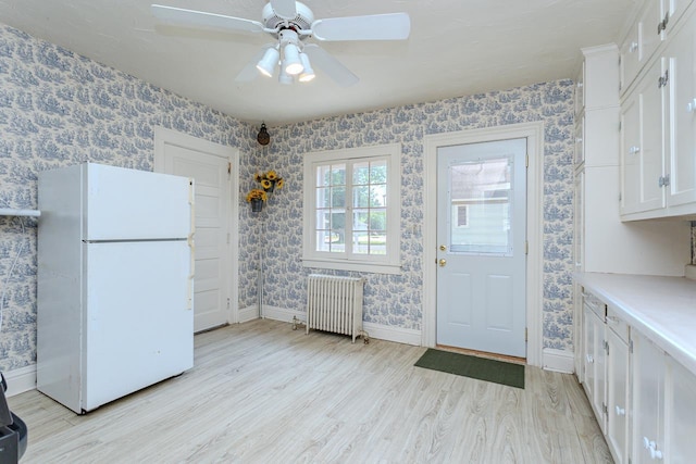 305 N Center Ave, Merrill, WI 54452 - kitchen with freestanding refrigerator, radiator heating unit, wallpapered walls, light wood-style flooring, and white cabinetry