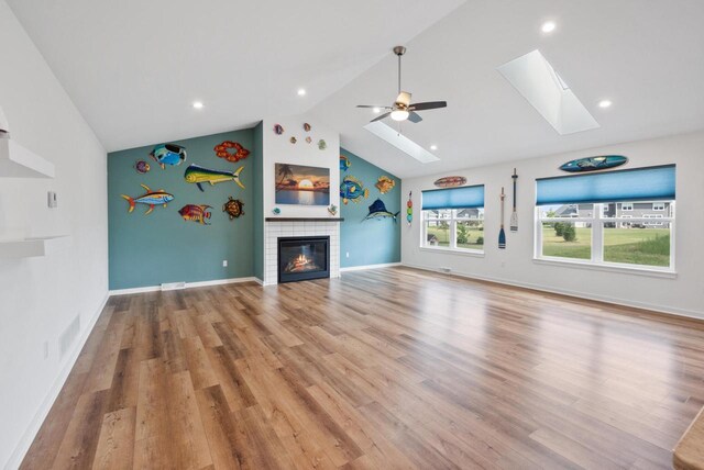 1451 Whalen Dr, Oconomowoc, WI 53066 - unfurnished living room with a skylight, a fireplace, wood finished floors, a ceiling fan, and high vaulted ceiling