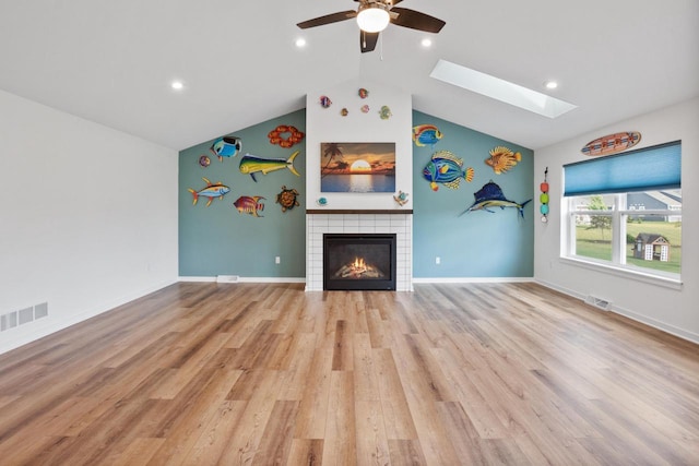 1451 Whalen Dr, Oconomowoc, WI 53066 - unfurnished living room with a skylight, a tiled fireplace, vaulted ceiling, a ceiling fan, and wood finished floors