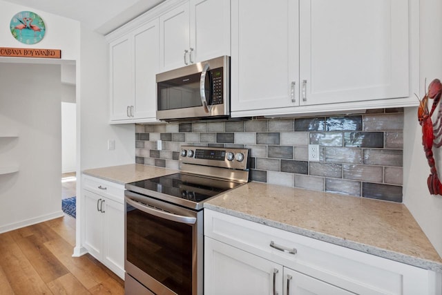 1451 Whalen Dr, Oconomowoc, WI 53066 - kitchen with appliances with stainless steel finishes, decorative backsplash, light wood-style flooring, and white cabinetry