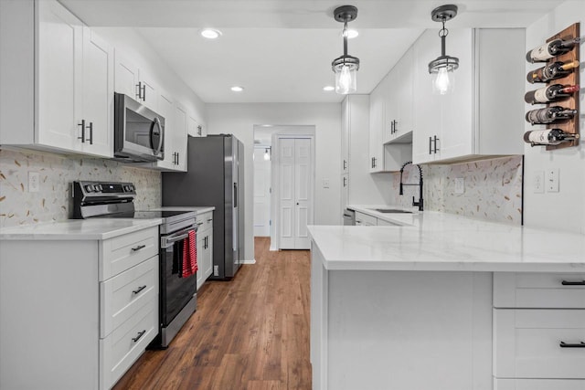 1152 Pilgrim Pkwy, Elm Grove, WI 53122 - kitchen with stainless steel appliances, a peninsula, white cabinets, wood finished floors, and recessed lighting