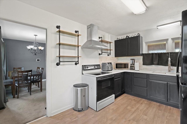 3021 Dwight St, Racine, WI 53403 - kitchen with electric range, wall chimney exhaust hood, stainless steel microwave, decorative backsplash, and a chandelier
