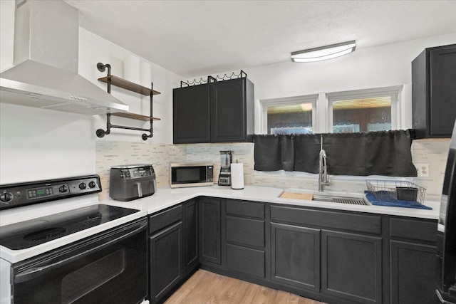 3021 Dwight St, Racine, WI 53403 - kitchen with electric stove, wall chimney range hood, stainless steel microwave, tasteful backsplash, and light countertops