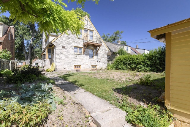 3940 N 64th St, Milwaukee, WI 53216 - view of side of home featuring a balcony, stone siding, and a yard