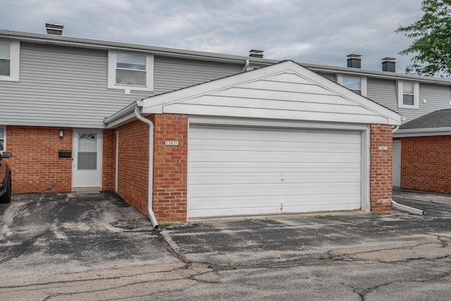 1363 Josephine St Unit E, Waukesha, WI 53186 - view of front facade with brick siding, a garage, a chimney, and driveway