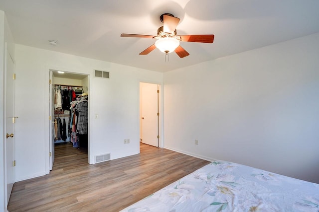 408 Juniper St, Brooklyn, WI 53521 - unfurnished bedroom featuring wood finished floors, a walk in closet, a ceiling fan, and a closet