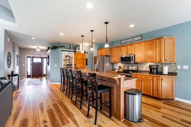 1255 Winterberry Rd, Oconomowoc, WI 53066 - kitchen featuring stainless steel appliances, light wood-style flooring, tasteful backsplash, a breakfast bar, and recessed lighting