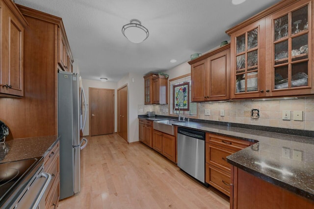 W203N16149 Pin Oak Cir, Jackson, WI 53037 - kitchen featuring stainless steel appliances, brown cabinets, light wood-style flooring, backsplash, and dark stone counters