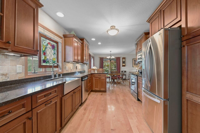 W203N16149 Pin Oak Cir, Jackson, WI 53037 - kitchen with stainless steel appliances, brown cabinetry, a chandelier, light wood-style flooring, and a peninsula