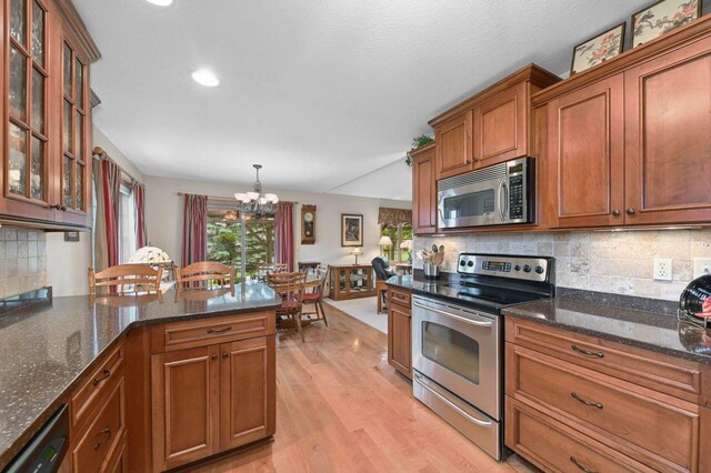 W203N16149 Pin Oak Cir, Jackson, WI 53037 - kitchen featuring stainless steel appliances, light wood-type flooring, brown cabinetry, a chandelier, and decorative backsplash