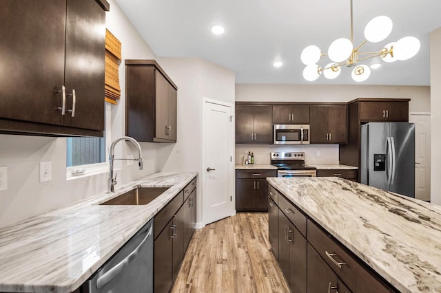 217 N Van Buren St, Green Bay, WI 54301 - kitchen featuring stainless steel appliances, light wood-style floors, dark brown cabinetry, light stone countertops, and hanging light fixtures