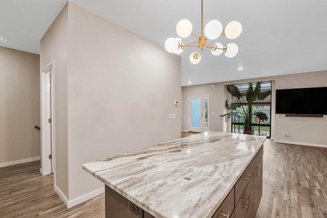 217 N Van Buren St, Green Bay, WI 54301 - kitchen featuring wood finished floors, a chandelier, light stone counters, a kitchen island, and decorative light fixtures
