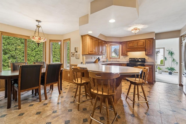 330 W Florida Ave, Appleton, WI 54911 - kitchen featuring black / electric stove, a peninsula, a kitchen breakfast bar, healthy amount of natural light, and wainscoting