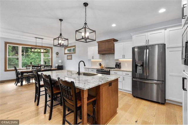 3735 Crest Ridge Ct, Eau Claire, WI 54701 - kitchen with appliances with stainless steel finishes, light wood-type flooring, white cabinetry, light stone counters, and backsplash