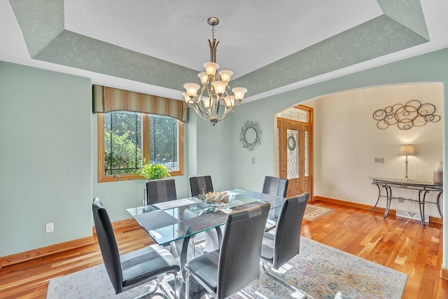 8668 47th Ave, Kenosha, WI 53142 - dining space featuring arched walkways, a raised ceiling, a chandelier, and light wood-style floors
