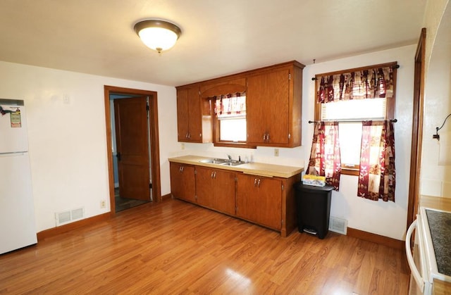 322 E N Ave, Little Chute, WI 54140 - kitchen featuring freestanding refrigerator, brown cabinets, light wood-style flooring, light countertops, and range