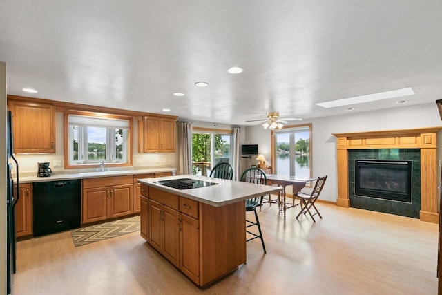 S7663 W Grandview Ave, Merrimac, WI 53561 - kitchen with black appliances, light wood-type flooring, a breakfast bar, a center island, and a tile fireplace