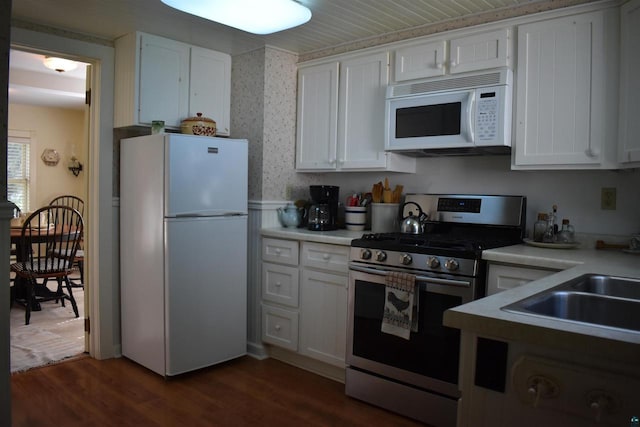 22630 Elm St, Cornucopia, WI 54827 - kitchen with white appliances, white cabinets, dark wood finished floors, light countertops, and wallpapered walls
