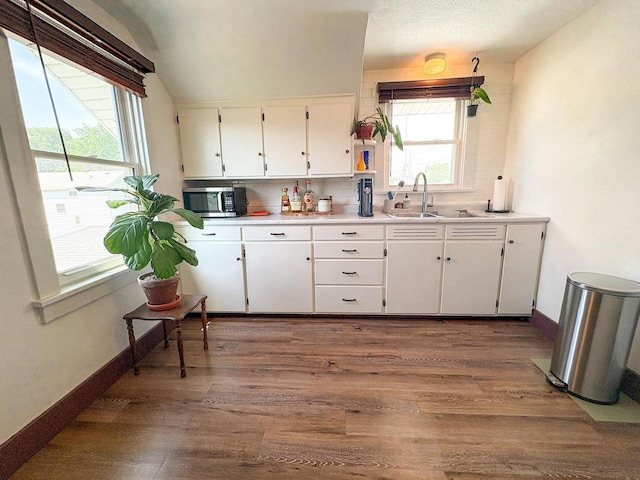 417 W 7th Ave, Oshkosh, WI 54902 - kitchen featuring stainless steel microwave, white cabinets, dark wood-type flooring, and light countertops