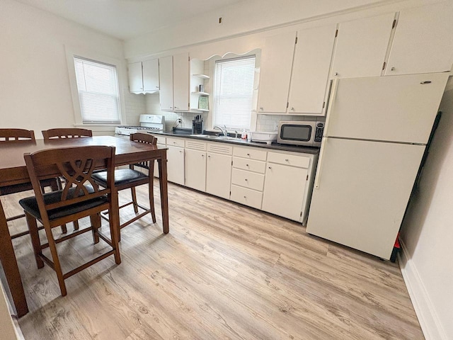417 W 7th Ave, Oshkosh, WI 54902 - kitchen with white appliances, light wood-style flooring, dark countertops, decorative backsplash, and open shelves