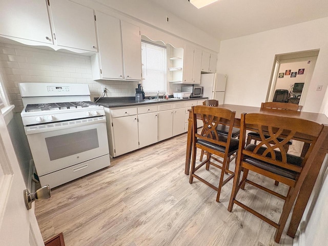 417 W 7th Ave, Oshkosh, WI 54902 - kitchen featuring white appliances, dark countertops, light wood-style flooring, open shelves, and tasteful backsplash
