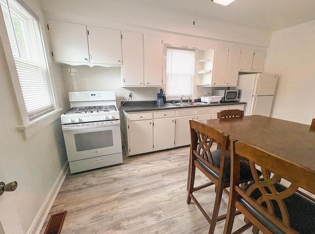 417 W 7th Ave, Oshkosh, WI 54902 - kitchen with white appliances, dark countertops, light wood finished floors, open shelves, and healthy amount of natural light