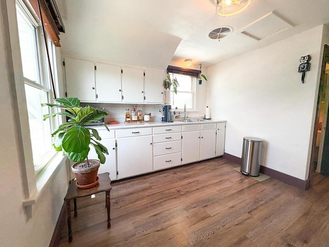 417 W 7th Ave, Oshkosh, WI 54902 - kitchen with dark wood-type flooring, white cabinetry, decorative backsplash, and light countertops