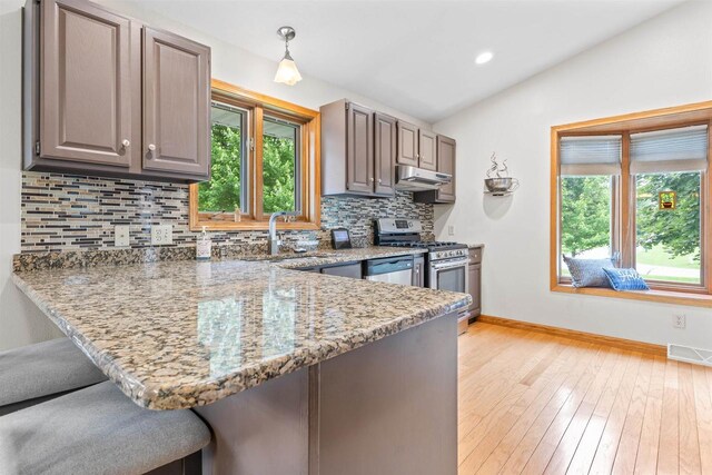 2570 Country Meadow Ct, Green Bay, WI 54313 - kitchen featuring stainless steel appliances, under cabinet range hood, a kitchen breakfast bar, healthy amount of natural light, and vaulted ceiling