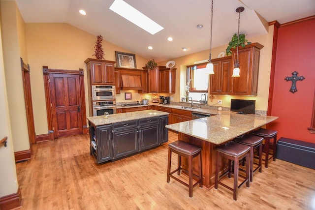 823 E Brandybrook Rd, Wales, WI 53183 - kitchen with vaulted ceiling, light stone counters, light wood-style floors, a kitchen island, and a breakfast bar