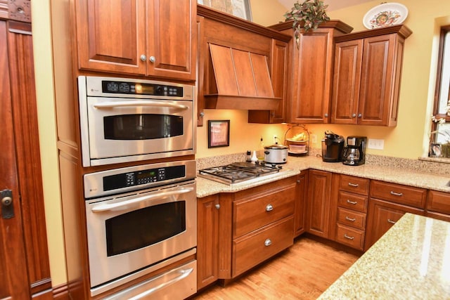 823 E Brandybrook Rd, Wales, WI 53183 - kitchen featuring appliances with stainless steel finishes, light wood finished floors, a warming drawer, and brown cabinets