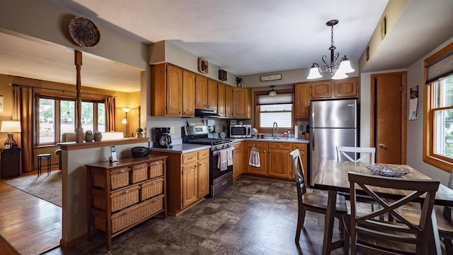 132 N Eagle St, Oshkosh, WI 54902 - kitchen with stainless steel appliances, exhaust hood, brown cabinets, and a chandelier